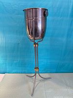 Full view of metal pedestal champagne bucket on tripod stand with brass collars