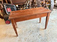 Full view of wood piano bench showing top surface and legs