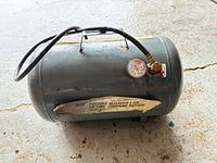 Side view of portable air tank showing gauge, hose, handle and label