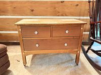 Front view showing three drawers, knobs, caster legs