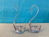 Front view of both clear glass swan figurines side by side