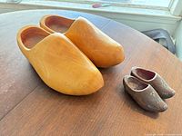 Large and small pairs of wooden clogs on tabletop