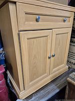 Full view of light oak cabinet showing drawer and doors closed