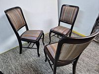 Three dark wood dining chairs shown together on carpet