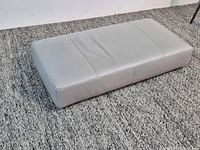 Top view of rectangular light grey leather ottoman on carpet