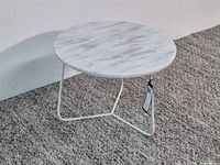 Full view of round marble top table with white metal legs