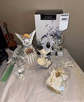 Group shot showing Heartwood Creek angel, two glass angels, porcelain angel with cup, packaged fabric angel, and original box