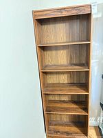 Full front view of tall brown laminate bookshelf
