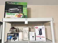 All items on shelving unit showing variety of appliances and drinkware