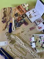 Overview of assorted necklaces, bracelets, earrings, brooches, watches and boxed jewelry on tabletop