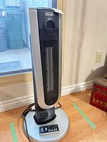 Full view of DeLonghi ceramic tower heater on base with power cord visible