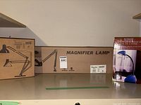 Three boxed lamps: Ikea Signatur, Magnifier Lamp, blue gooseneck lamp package