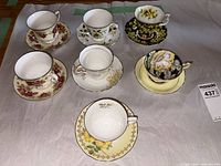 Six teacup and saucer sets arranged on paper
