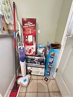 Group view of all cleaning items including steam mop, boxed vacuum, dusting kit, replacement pads, and floor mop