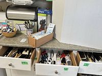 Countertop view showing bread box, knife set box, assorted utensils in open drawers