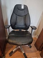 Front view of black swivel office chair showing wear on seat and armrests