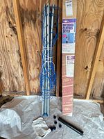 Folded galvanized steel drying rack with blue lines, plastic caps, ground sleeve and instructions