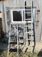 Both ladders leaning against shed