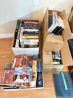 Overview of three boxes filled with VHS tapes DVDs and CDs