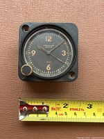 Front view of clock with measuring tape showing roughly 2.25 inch width