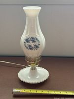 Full view of milk glass lamp with cord and ruler for scale