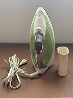 Front view of Black+Decker iron standing upright with power cord and water pitcher