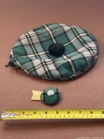 Large green tartan tam and mini tam pin beside ruler for scale