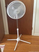 Front view of assembled white pedestal fan showing grille and base