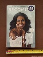 Front cover showing title, author and $25 price label next to ruler for scale