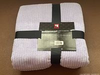 Front view of folded lavender ribbed throw with product tag and ribbon