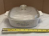 Front view of casserole with lid and tape measure indicating size