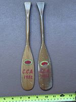 Two miniature paddles full length beside ruler