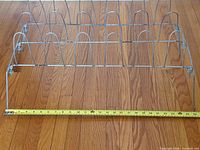 Top view of entire metal shoe rack with tape measure across width