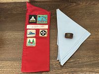 Full view of red sash with patches, light blue neckerchief, and brown leather slide