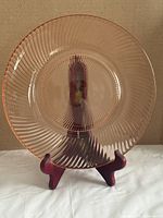 Front view of rose-pink swirl glass plate on stand