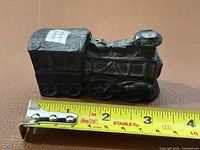 Side view of coal locomotive with tape measure showing approximately 4 in length