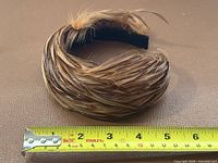 Full view of feather-covered headband with tape measure showing length