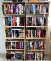 Full frontal view of bookcase filled with books showing six shelves and light maple finish