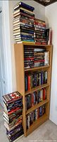 Full view of bookcase with four shelves and two loose stacks of hardcovers