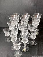 Group of 16 clear cut crystal stemmed glasses arranged in rows