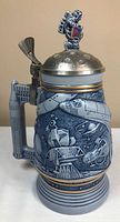 Front view of ceramic stein showing space motif and pewter lid with astronaut finial