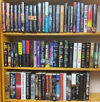 Three shelves of hardcover and paperback fantasy/science-fiction books