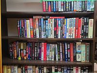 Three shelves filled with hardcover thriller, military and mystery books
