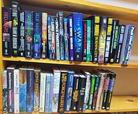 Two shelves of assorted science fiction and fantasy books showing Mars trilogy, Battlestar Galactica paperbacks, assorted hardcovers
