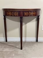 Front view of demilune table showing inlaid apron and three legs