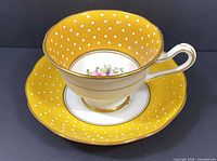 Teacup on saucer, showing exterior yellow polka dot pattern and gold trim