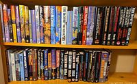 Two full shelves of assorted Anne McCaffrey hardcovers and paperbacks plus additional authors