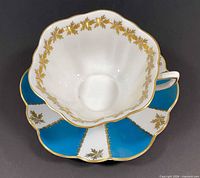 Cup nested on saucer showing turquoise, white and gold Stratford pattern