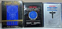Front view of all three Star Trek publications: blueprint box, technical manual binder, medical manual sealed