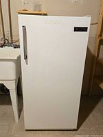 Front view of closed white upright refrigerator showing handle and exterior condition